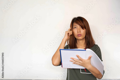Lady holding book in hand,raise finger touch her head and thinking,with interested feeling