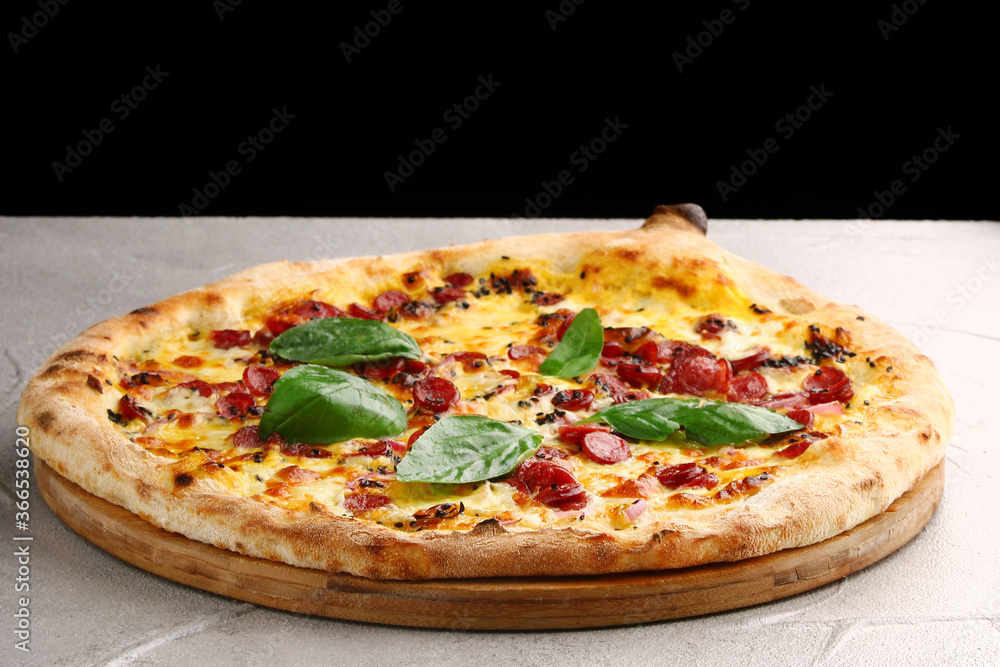 jalapeno pizza with sausages close up on gray concrete or stone table and black background for copy space