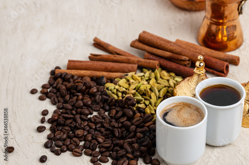 Cup of coffee with roasted beans, seeds and cinnamon
