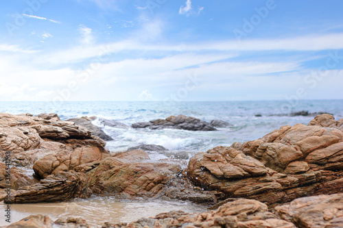 Water splashing. Crystal clear sea water beating against the rocks and cliffs. Blue sky above the beach in the sun zenith refreshing drops of ocean water. Sea waves break on the shore after a storm