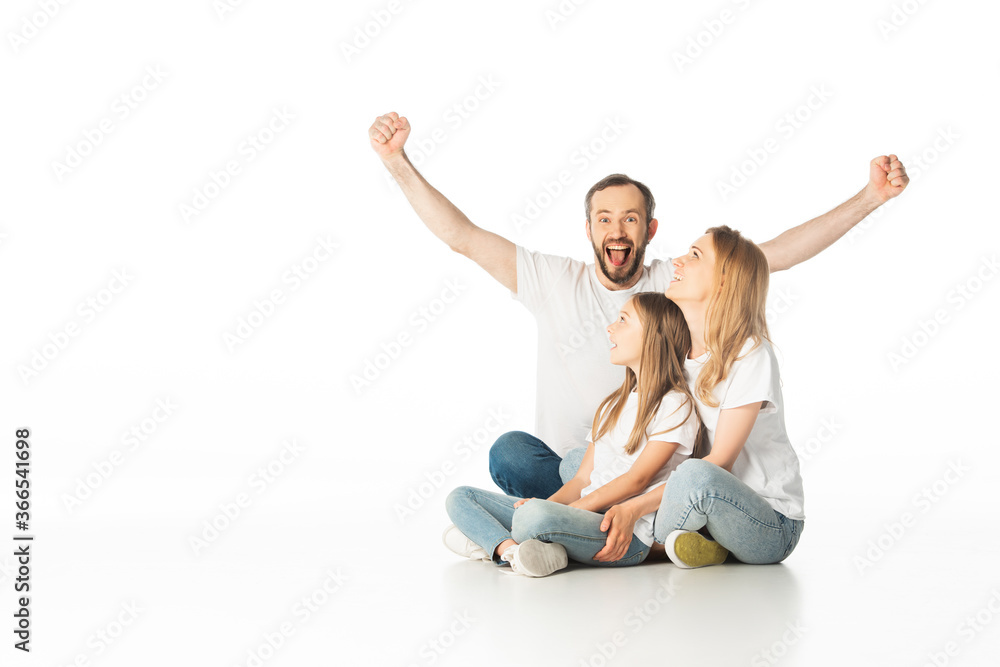 happy family sitting on floor with crossed legs while man showing yes gesture isolated on white happy family sitting on floor with crossed legs while man showing yes gesture isolated on white