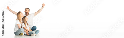 happy family sitting on floor with crossed legs while man showing yes gesture isolated on white, panoramic shot