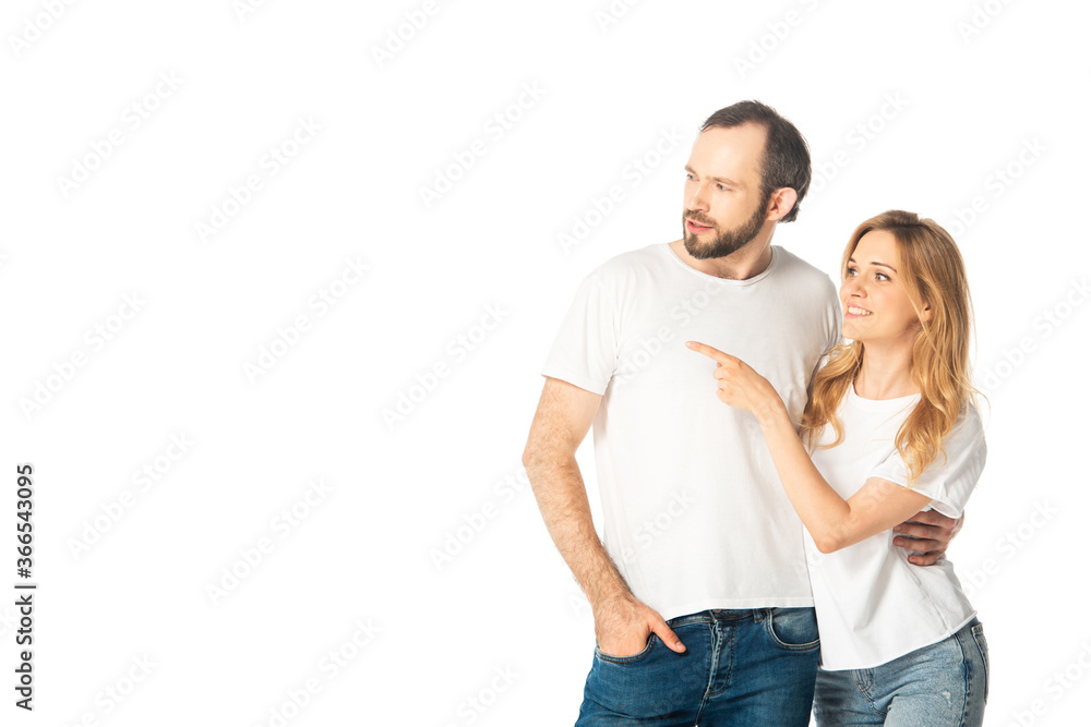 cheerful adult couple in white t-shirts pointing with finger aside isolated on white
