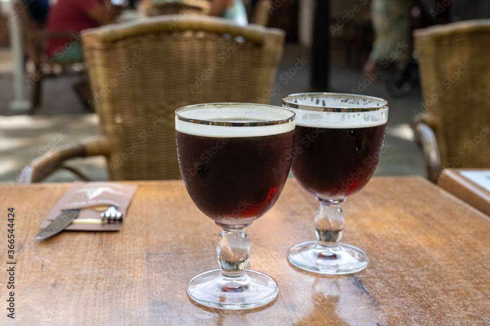 Glasses with cold dark strong Belgian beer served outdoor Glasses with cold dark strong Belgian beer served outdoor