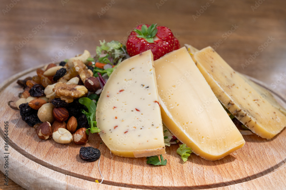 Tasting wooden board with different types of Belgian hard abbey cheeses, nuts and fruits