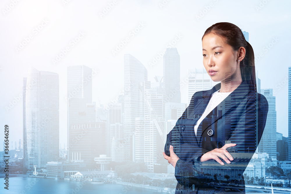 Prosperous Asian businesswoman in suit in crossed arms pose. Singapore cityscape. The concept of woman in business. Financial downtown. Double exposure. Prosperous Asian businesswoman in suit in crossed arms pose. Singapore cityscape. The concept of woman in business. Financial downtown. Double exposure.