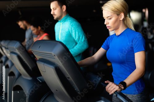 Young people running on a treadmill in modern gym