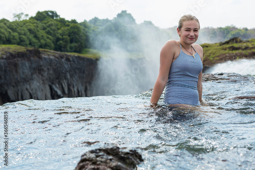 Young teenage girl at the Devils Pool, standing in the water above  Victoria Falls, Zambia photo