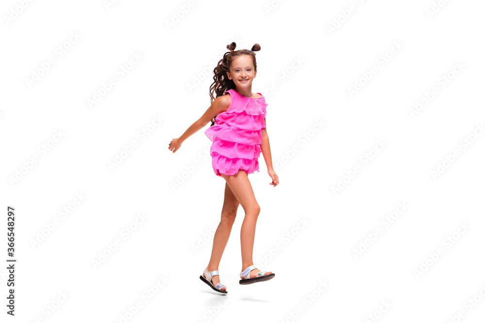 Happy child, little and emotional caucasian girl jumping and running isolated on white background. Looks happy, cheerful, sincere. Copyspace for ad. Childhood, education, happiness concept.