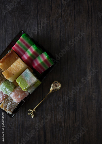 Singapore Peranakan Food Flat Lay. Peranakan Food on Wooden Table. Peranakan Kueh with Copy Space on Wooden Table. Asian Desserts. Nonya Kueh Lapis, Bingka Ubi, Kosui, Talam.