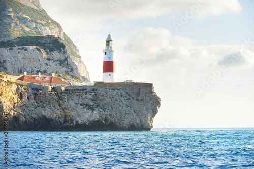 Trinity lighthouse at the rocky shore (cliffs) of the Europa Point. British Overseas Territory of Gibraltar, Mediterranean sea. National landmark, sightseeing, travel destination, famous place, travel
