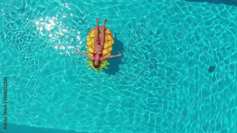 aerial shot from the drone of young woman relaxing on the mattress in the pool aerial shot from the drone of young woman relaxing on the mattress in the pool