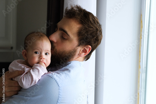 Modern father in his arms holds his little child while standing in the kitchen