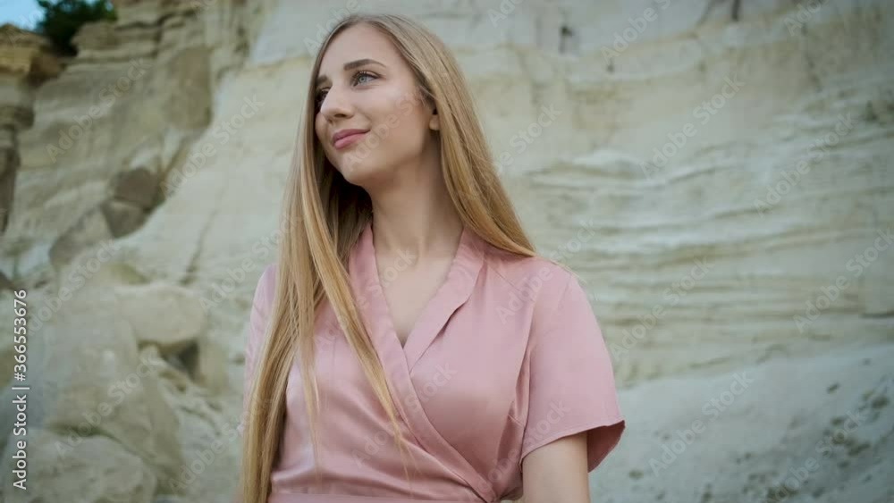 Tourist young woman of Caucasian appearance blonde in a pink dress with a hood and a handbag walks through the canyon and enjoys the beauty of the sand Tourist young woman of Caucasian appearance blonde in a pink dress with a hood and a handbag walks through the canyon and enjoys the beauty of the sand