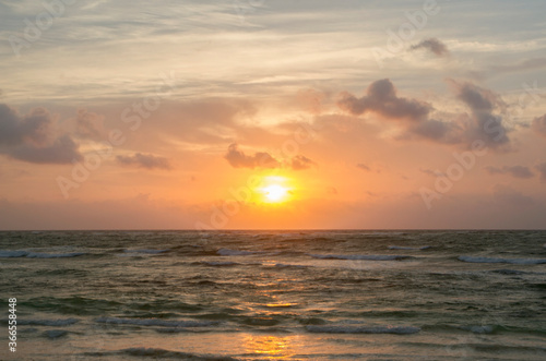 Heavens. Dramatic beach seascape. Beautiful sunset sky with orange sun rays and clouds  over the sea and ocean waves. The reflection of the sun in the pure water. 