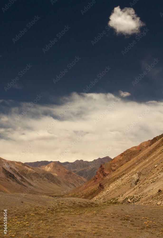 Deserted landscape. Vertical photo of the valley, arid mountains and grassland under a deep blue sky. 
