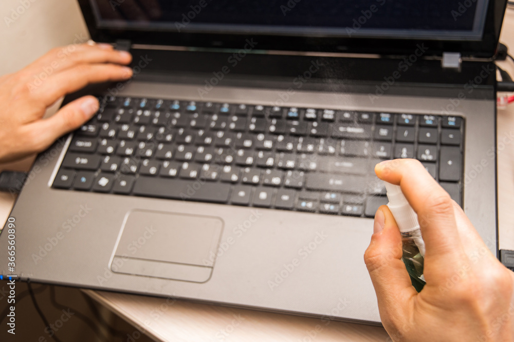 Close up. Male hands disinfect the laptop keyboard with the help of alcohol spray disinfectant. Close up. Male hands disinfect the laptop keyboard with the help of alcohol spray disinfectant.