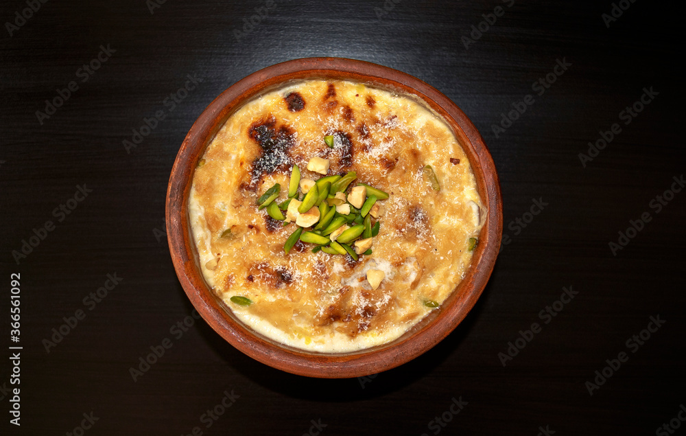 Traditional Arabic, eastern dessert Om Ali. Top view. Egyptian Bread Pudding in a brown bowl on dark wooden table. Top view. Egypt sweet pastry dessert Traditional Arabic, eastern dessert Om Ali. Top view. Egyptian Bread Pudding in a brown bowl on dark wooden table. Top view. Egypt sweet pastry dessert