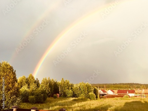 Bright sun after rain and a rainbow in the sky over the countryside. High quality photo