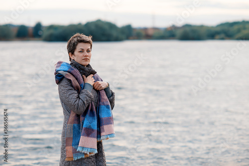 Woman in grey coat and purple scarf  by the lake,