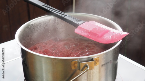 the cook cooks raspberry jam in a pot on the stove. raspberry jam.