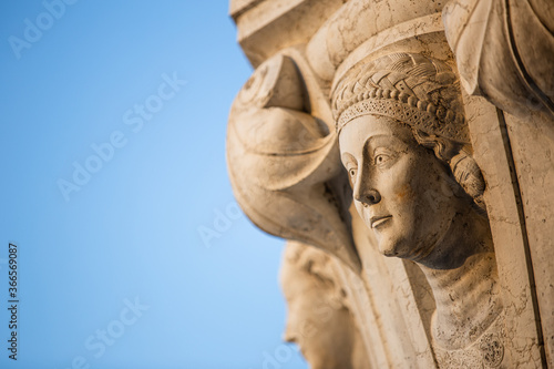 Close up of angelic face carved into a pillar of San Marco square in golden hour morning light