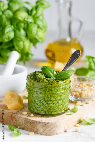 Homemade basil pesto sauce in a glass jar. Vegetarian food. Still life photography. Selective focus