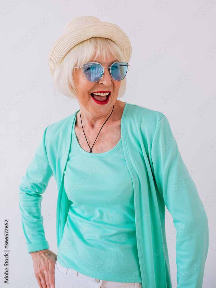 senior (old) stylish cheerful woman in straw hat and sunglasses and turquoise clothes. Summer, travel, anti age, joy, retirement, freedom concept