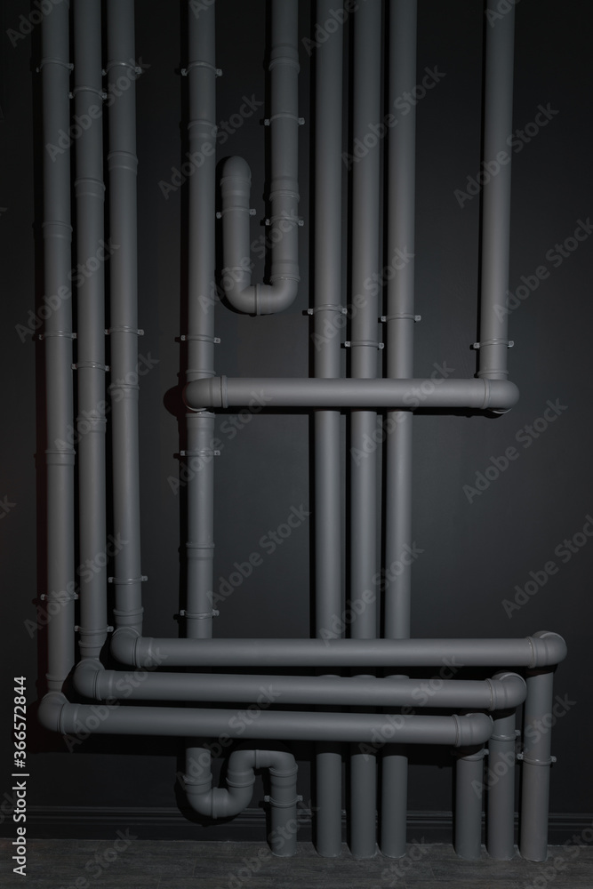 Obraz premium Complicated Gray plastic drainage pipes system on wall