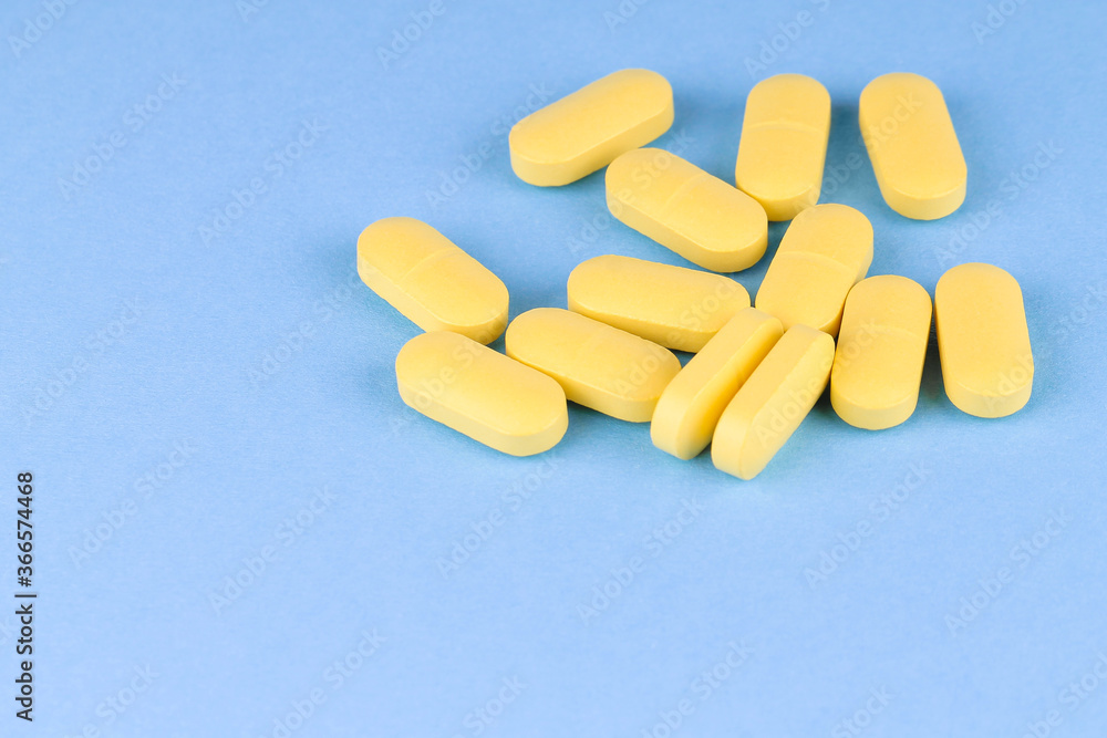 The yellow pills scattered onto the blue surface. Medicine. The yellow pills scattered onto the blue surface. Medicine.