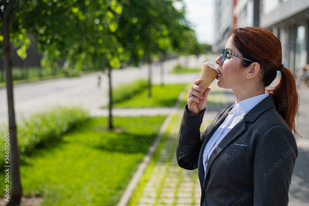 A business woman walks outdoors and enjoys eating vanilla ice-cream on a sunny summer day. Portrait of a smiling girl in a white shirt and a jacket with an ice cream cone. A business woman walks outdoors and enjoys eating vanilla ice-cream on a sunny summer day. Portrait of a smiling girl in a white shirt and a jacket with an ice cream cone.