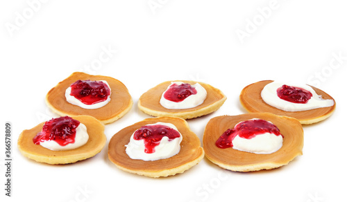 Pancakes with sour cream and raspberry jam on white background