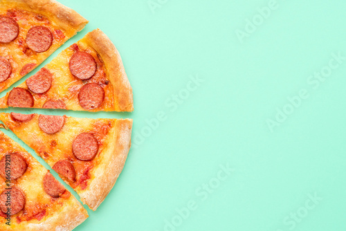 Pepperoni pizza top view. Sliced pizza isolated on a green background.