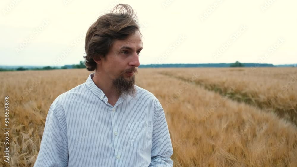 A 30-year-old agronomist with a Caucasian appearance and a beard walks in a field on a wheat or barley plantation with a magnifying glass and does research A 30-year-old agronomist with a Caucasian appearance and a beard walks in a field on a wheat or barley plantation with a magnifying glass and does research