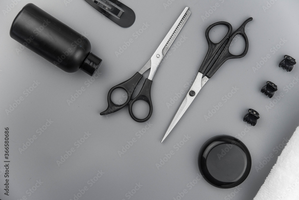 Professional hair dresser tools with copy space. Hair stylist equipment set on gray background. Scissors, brush, hairbrush, balm flat lay top view. Professional hair dresser tools with copy space. Hair stylist equipment set on gray background. Scissors, brush, hairbrush, balm flat lay top view.