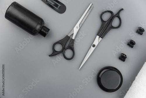 Professional hair dresser tools with copy space. Hair stylist equipment set on gray background. Scissors, brush, hairbrush, balm flat lay top view.