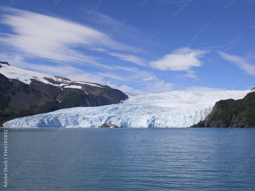 Glacier Meets Water of Pacific Bay on Alaskan Coast with Blue Sky and Clouds 
