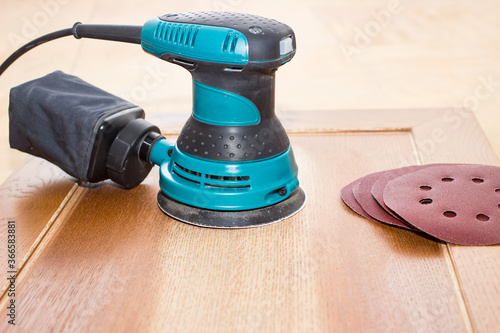 Sand paper and sand machine remove varnish from old furniture. Electrical tools of carpenter joiner and restorer.