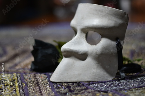 White, traditional, generic, Venetian mask in papier mache with a black rose on blurred background.
selective focus, space for copy.