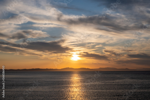 Sunrise, sunset clouds. Twilight, dusk cloudy sky over sea water, mountain silhouette © Rawf8