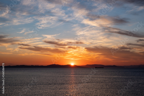 Sunrise, sunset clouds. Twilight, dusk cloudy sky over sea water, mountain silhouette