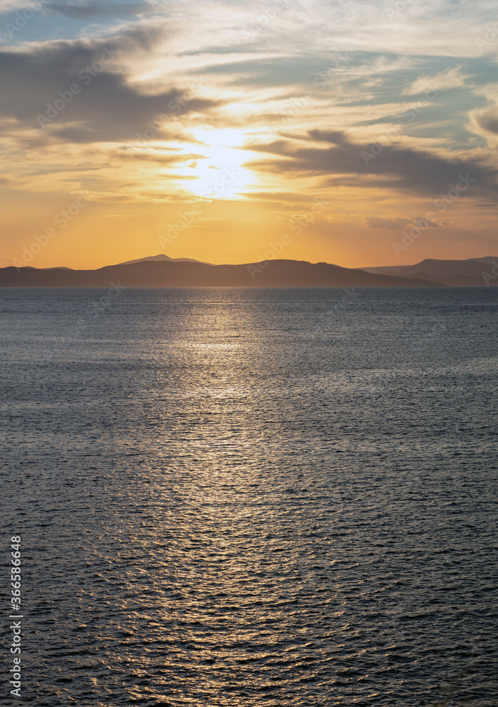 Sunrise, sunset clouds. Twilight, dusk cloudy sky over sea water, mountain silhouette