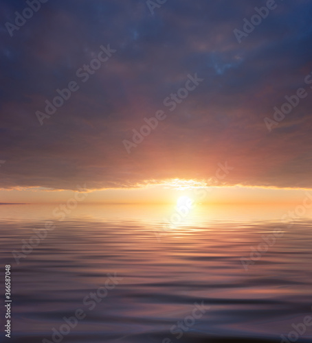 Sunset over a calm ocean with bright rays of the sun and storm clouds.