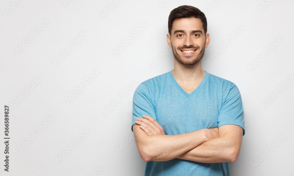 Banner of young handsome man wearing blue t-shirt, standing with crossed arms, isolated on studio gray background Banner of young handsome man wearing blue t-shirt, standing with crossed arms, isolated on studio gray background