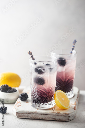 Refreshing Blackberry Lemonade with ice in crystal glasses on white background