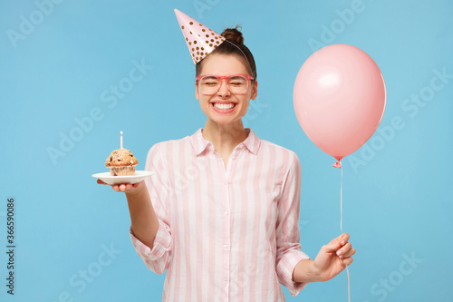Photography Young happy birthday girl in hat, holding pink balloon in one hand and holiday c