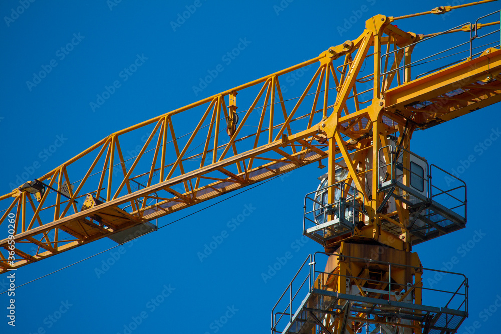 Yellow tower crane working on building against blue sky, selective focuse