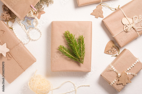 several Christmas gift boxes in eco friendly style on a white background, decorating gifts with wooden figures and natural materials, a box decorated with a spruce branch