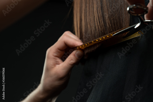 Fototapeta Naklejka Na Ścianę i Meble -  Cropped shot of hairdresser doing haircut to young woman in beauty salon