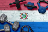 Paraguay sports club concept. Top view of heavy weight plates with iron bar on national background.